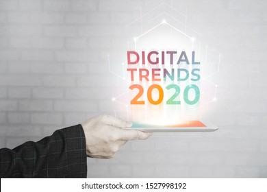 Man Hand Holding White Tablet With Digital Trends 2020 On Screen. New Trends Digital Marketing, Business And Technology Concept.