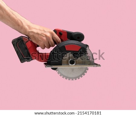 Man hand holds Brushless Cordless circular saw from left top corner on pink color background