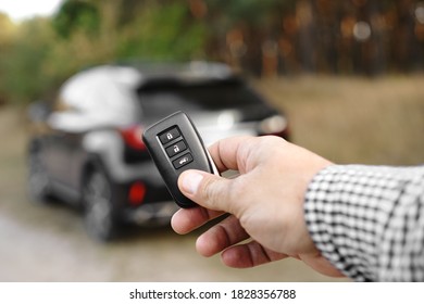 Man Hand Holds Car Key Against Blurred Car. New Car Concept.