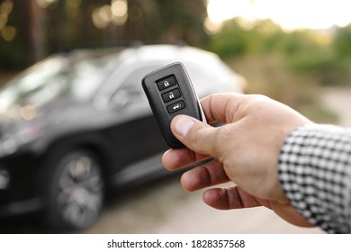 Man Hand Holds Car Key Against Blurred Car. New Car Concept.