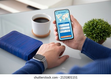 Man Hand Holds Phone With Application Searching Air Tickets On The Screen Over Desk In Office