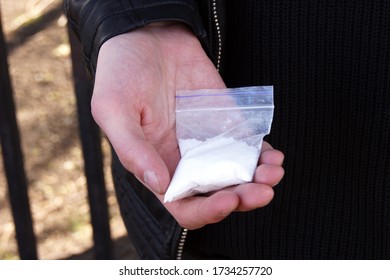 Man hand holds plastic packet with cocaine or another drugs, drug abuse and danger addiction concept, selective focus.