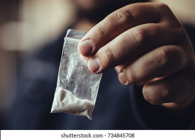 Man Hand Holds Plastic Packet Or Bag With Cocaine Or Another Drugs, Drug Abuse And Danger Addiction Concept, Selective Focus, Toned