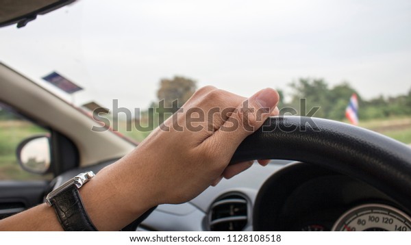 a man hand holind steering\
wheel