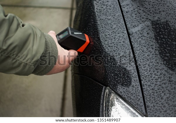 Man hand inspecting car paint with a paint\
meter. Checking the paint of the\
car.