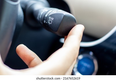 man hand on windshield wiper and washer controls,shifter or on steering wheel.detail in a modern hybrid car,automatic transmission.drive safe,parts from vehicles interior.