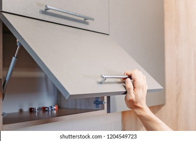 man hand open kitchen cupboard with handle, close up