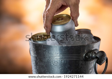 man hand picking cold beer can from ice cooler tank