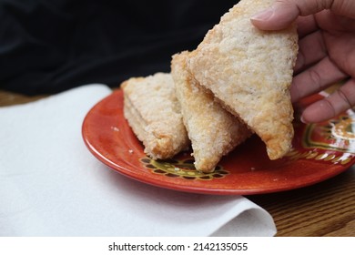 Man hand picking Turnovers Apple, apple pie, served in an orange plate, Turnovers Apple is a popular dish in America.