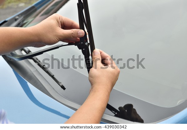man hand picking up windscreen\
wiper or Mechanic check old wiper blade on customers sedan car.\
