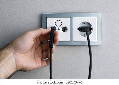 A Man Hand Plugging Antenna Cable To The TV Outlet