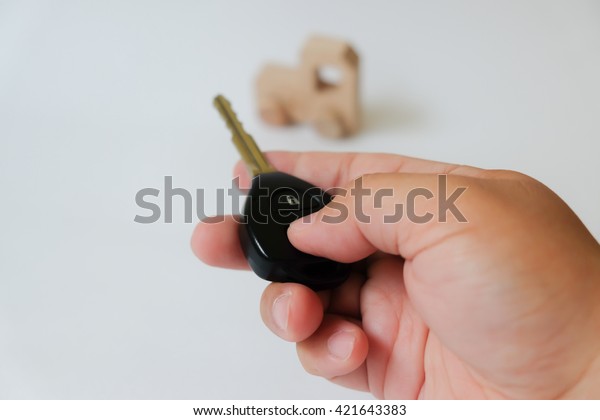 A man hand press button of car\
key to wooden car toy on gray background with\
copyspace