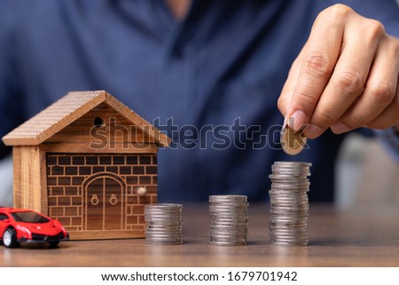 Man hand putting coin to save money buy a house and super car, Business concept.