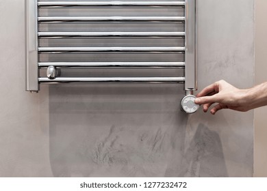 The Man Hand Regulates The Temperature In The Heated Towel Rail In Bathroom