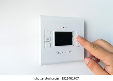 Man hand setting the room temperature on a modern programmable thermostat water heater (boiler). Smart home.