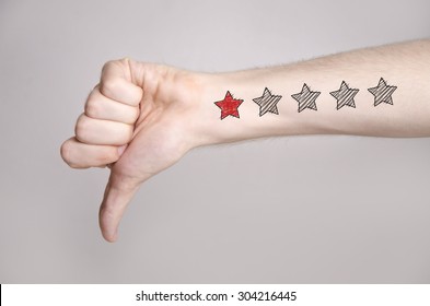Man hand showing thumbs down and one star rating on the arm skin. Dislike