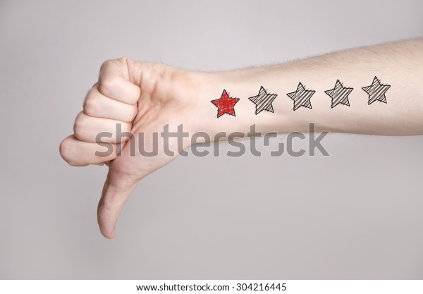 Man hand showing thumbs down and one star rating
on the arm skin. Dislike