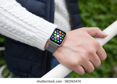 Man hand and smart touch watch with home screen icons apps on street 