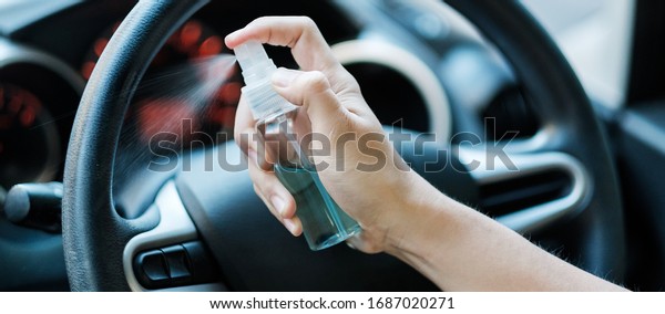 man hand\
spraying alcohol sanitizer on steering wheel in his car, against\
Novel coronavirus or Corona Virus Disease (Covid-19). Antiseptic,\
Hygiene and Healthcare\
concept