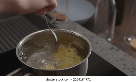 man hand stir fettuccine in boiling water in saucepan - Shutterstock ID 2164194971