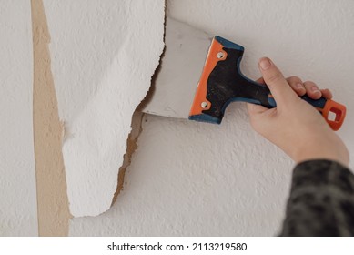 Man Hand Tearing Off Old Wallpaper With Scraper From Wall.