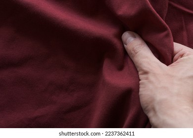 man hand touching red wine color cotton fabric, shallow focus