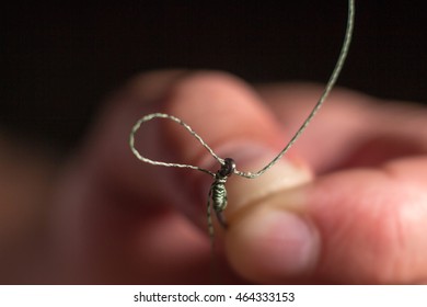 Man hand tying a fishing hook. Tie the rig.  Selective focus. Tie Hook Close Up. Tie Fishing Hook  Tying a fishing hook Process. Tie the KD rig and catch more carp. 5/6 - Powered by Shutterstock