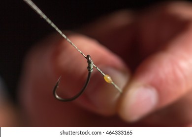 Man hand tying a fishing hook. Tie the rig.  Selective focus. Tie Hook Close Up. Tie Fishing Hook  Tying a fishing hook Process. Tie the KD rig and catch more carp. 6/6 - Powered by Shutterstock