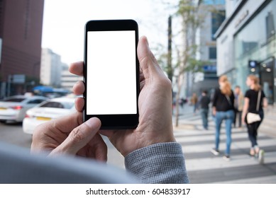 Man Hand Using Blank Screen Mobile Smart Phone With Blurred Background Of People Walking On Pathway And Car Driving On The Road In The City, Internet Application On Smart Phone