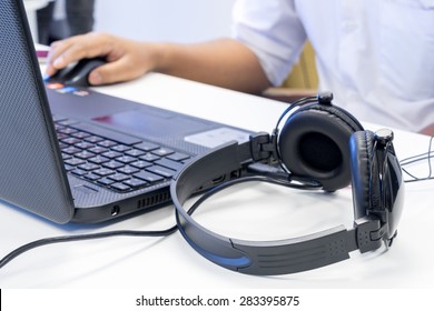 Man hand using keyboard and mouse to control laptop with headphone beside, working in music editing studio production
