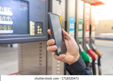 Man hand using mobile phone at gas pump station to pay for gasoline. Automotive industry or transportation and ownership concept. Delivery service concept. Isolated