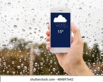 man hand using mobile smart phone with glass window full of water droplets of raining day view with weather forecast widget mobile application program template. - Shutterstock ID 484897642