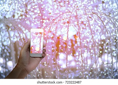 a man hand using white mobile phone with blurred light of the night