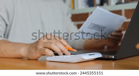 man hand write on notebook and calculate on calculator about debt bills pay monthly at the table in office and manage expense payroll for money risk and crisis financial and inflation concept