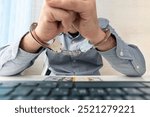 a man in handcuffs is sitting at his workplace with a computer and money in dollars.. The concept of bribery and criminal crimes in the cyber sphere. internet censorship