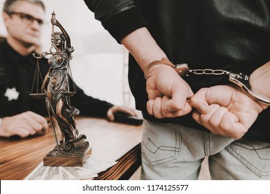 A Man In Handcuffs Stands In Front Of Policeman. Femida Statue. Work Together. Ask A Question. Citizen's Protection. Detainee Arrest. Public Order. Crime Scene. Suspect Questionee.