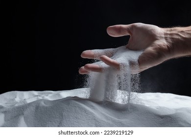 Man with handful of white dry sand in her hands, spilling sand through fingers on black background. Concept of flow of life. Close up of grains of pure natural mineral quartz. - Powered by Shutterstock