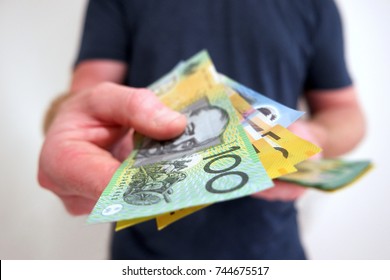 Man handing out hundreds and fifties Australian dollar bills. Buying, paying, handing out money, showing money.