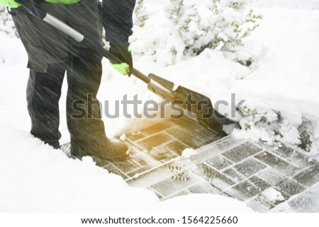 Man handle black shovel or snow sled and  removing snow from stairs sidewalk during eavy snow storm. Safety in winter concept.
