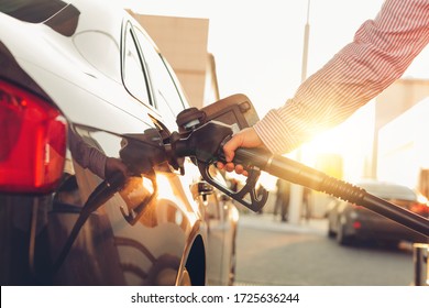 Man handle pumping gasoline fuel nozzle to refuel at petrol station. Transportation and ownership concept. Sunset lighting - Shutterstock ID 1725636244