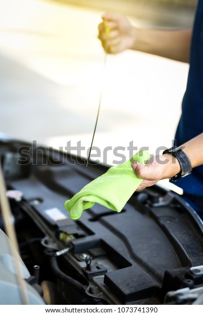 Man hands checking lube\
oil level of car engine from deep-stick for service and maintenance\
concept.