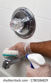 Man Hands Cleaning Bath Tub Faucet Wearing Silicone Gloves And Spraying With Liquid.