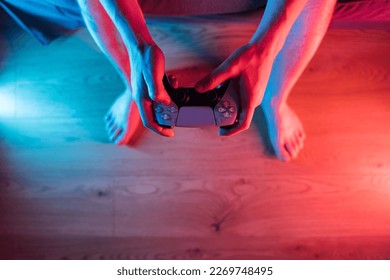 Man hands with game controller in neon light, top view