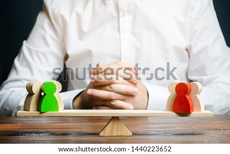A man with hands in the gesture of a lock and looks at the red and green standoff groups on a scales. conflict resolution and the search for a compromise in the dispute. Research argument of each side