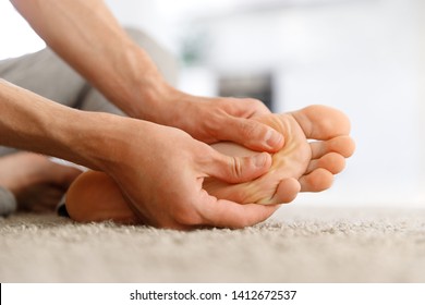 Man Hands Giving Foot Massage To Yourself To Relieve Pain After A Long Walk, Suffering With Flat Feet, Close Up, Soft Focus, Indoors. Flat Feet, Leg Fatigue.  