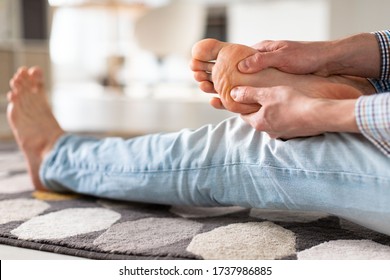 Man Hands Giving Foot Massage To Yourself To Relieve Pain After A Long Walk, Due To Uncomfortable Shoes, Suffering From Flat Feet, Close Up, Soft Focus, Indoors. Flat Feet, Leg Fatigue.  