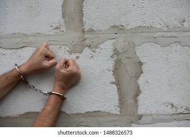 Man hands in handcuffs with clenched fists on a grey wall background. Arrested criminal. Copy space, Moc up - Powered by Shutterstock