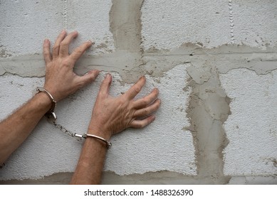 Man hands in handcuffs with spread fingers on a grey wall background. Arrested criminal. Copy space, Moc up - Powered by Shutterstock