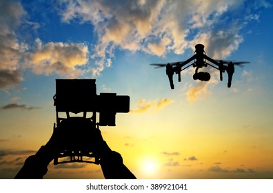 Man hands handling drone against sunset silhouettes