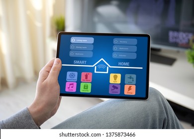 man hands holding computer tablet with app smart home on screen in the home room